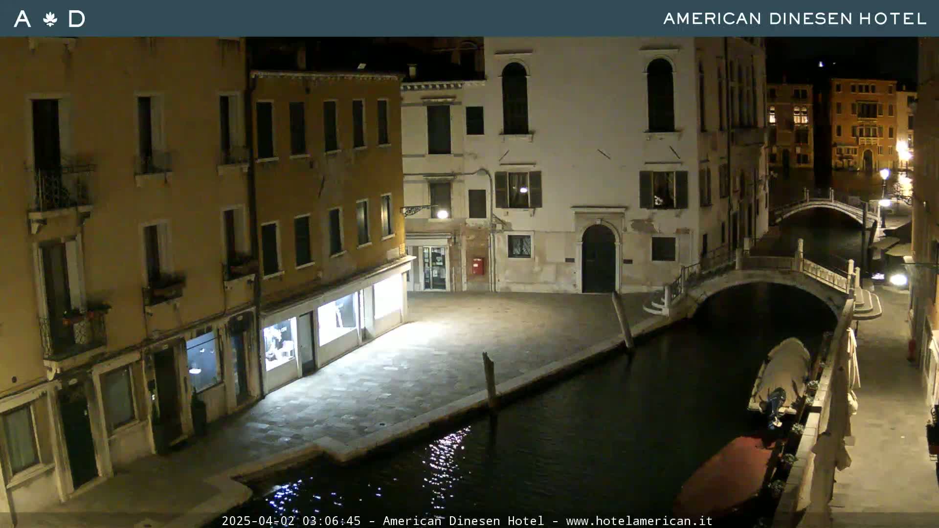A nighttime view of a canal in Venice, Italy, with buildings lining the waterway and a small boat moored nearby.