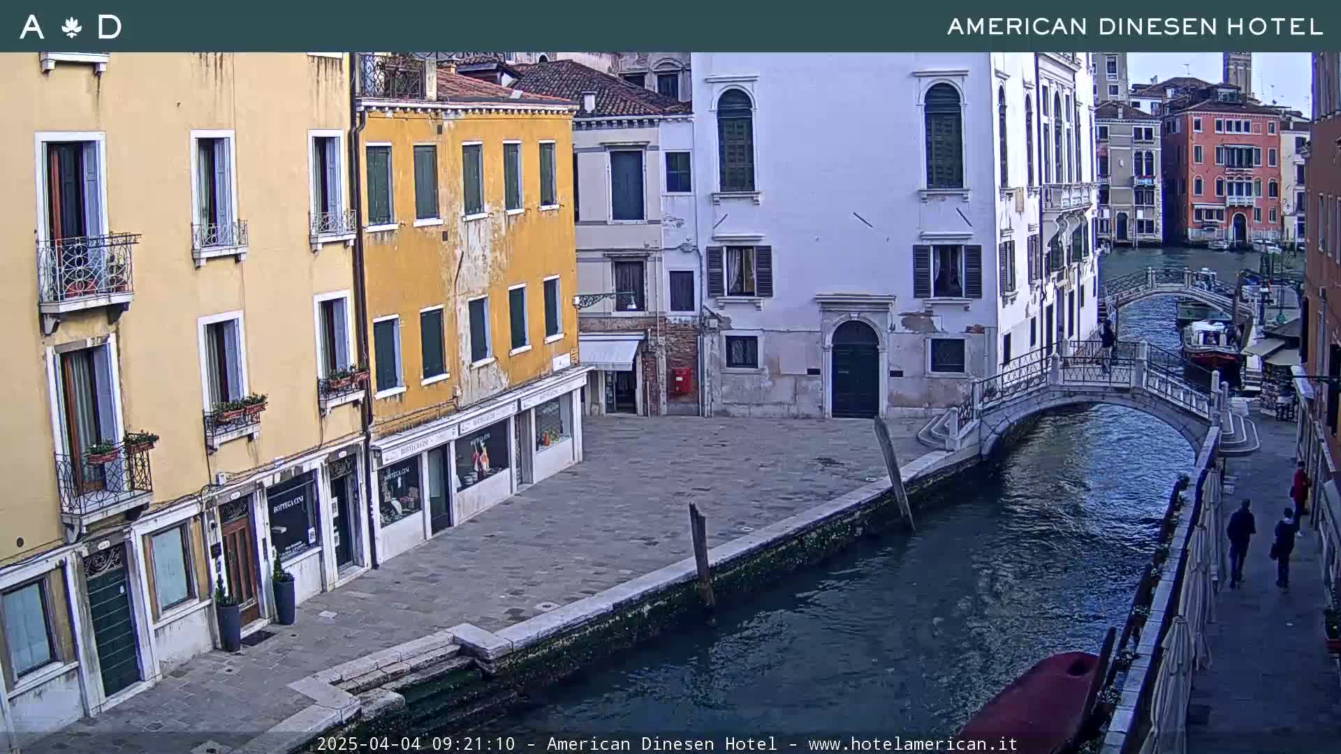A canal in Venice, Italy, with several buildings lining its banks and a small footbridge crossing it on an overcast day.