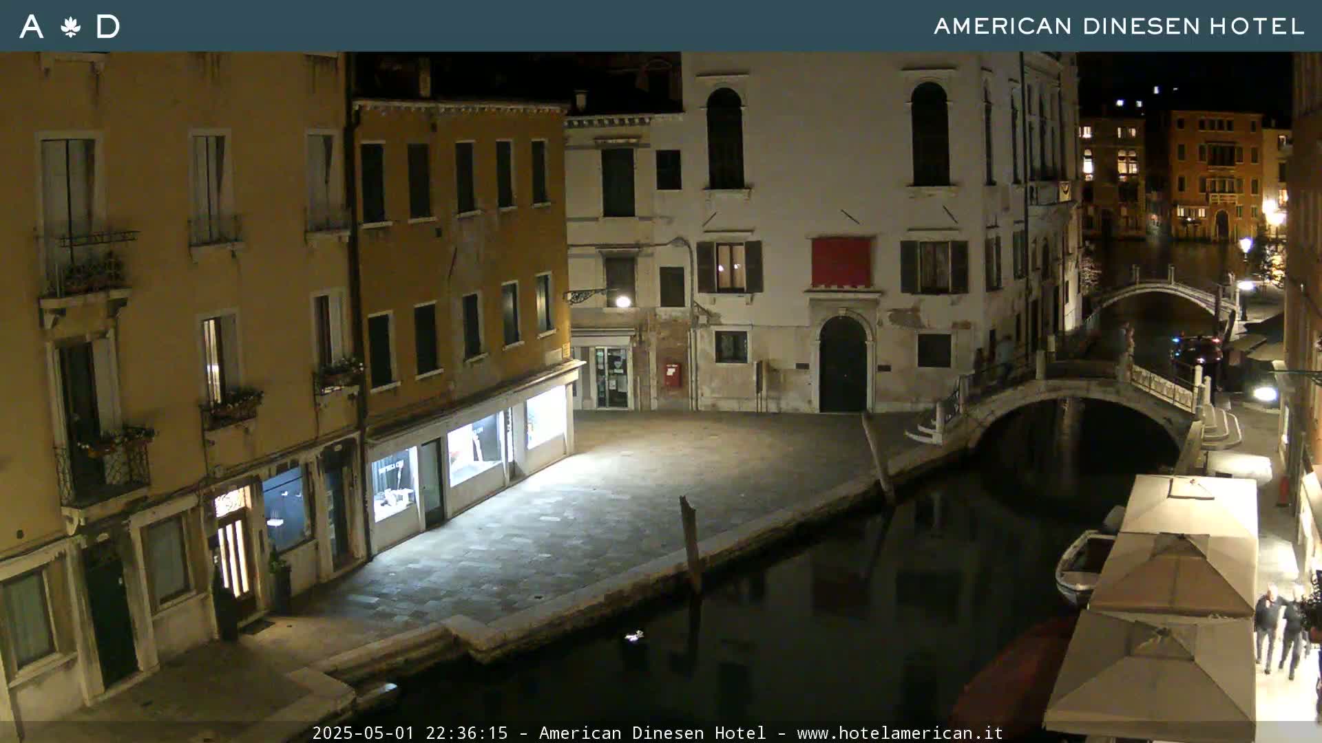 A nighttime view of a canal in Venice, showing buildings lining the waterway and a small bridge crossing the canal.