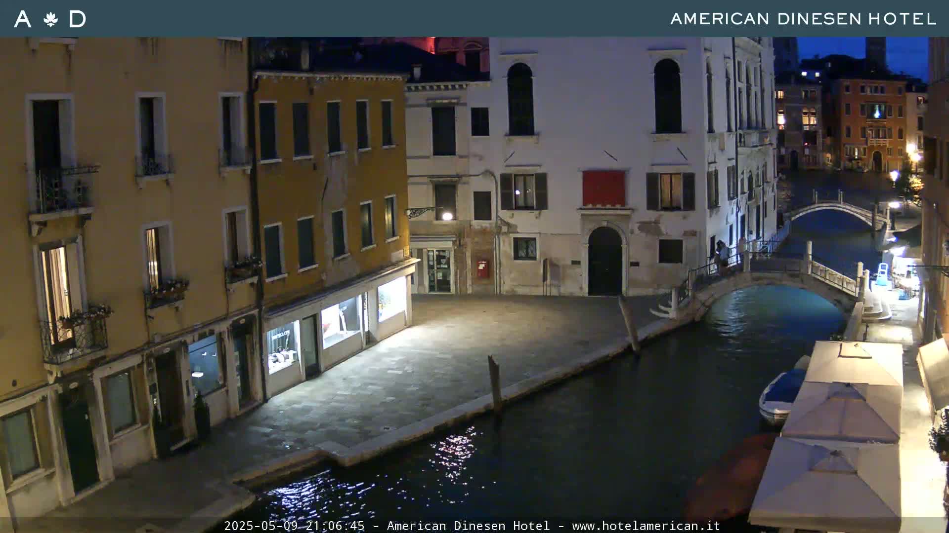 A nighttime view of a canal in Venice, Italy, showing several buildings illuminated along the waterway with a bridge crossing the canal.