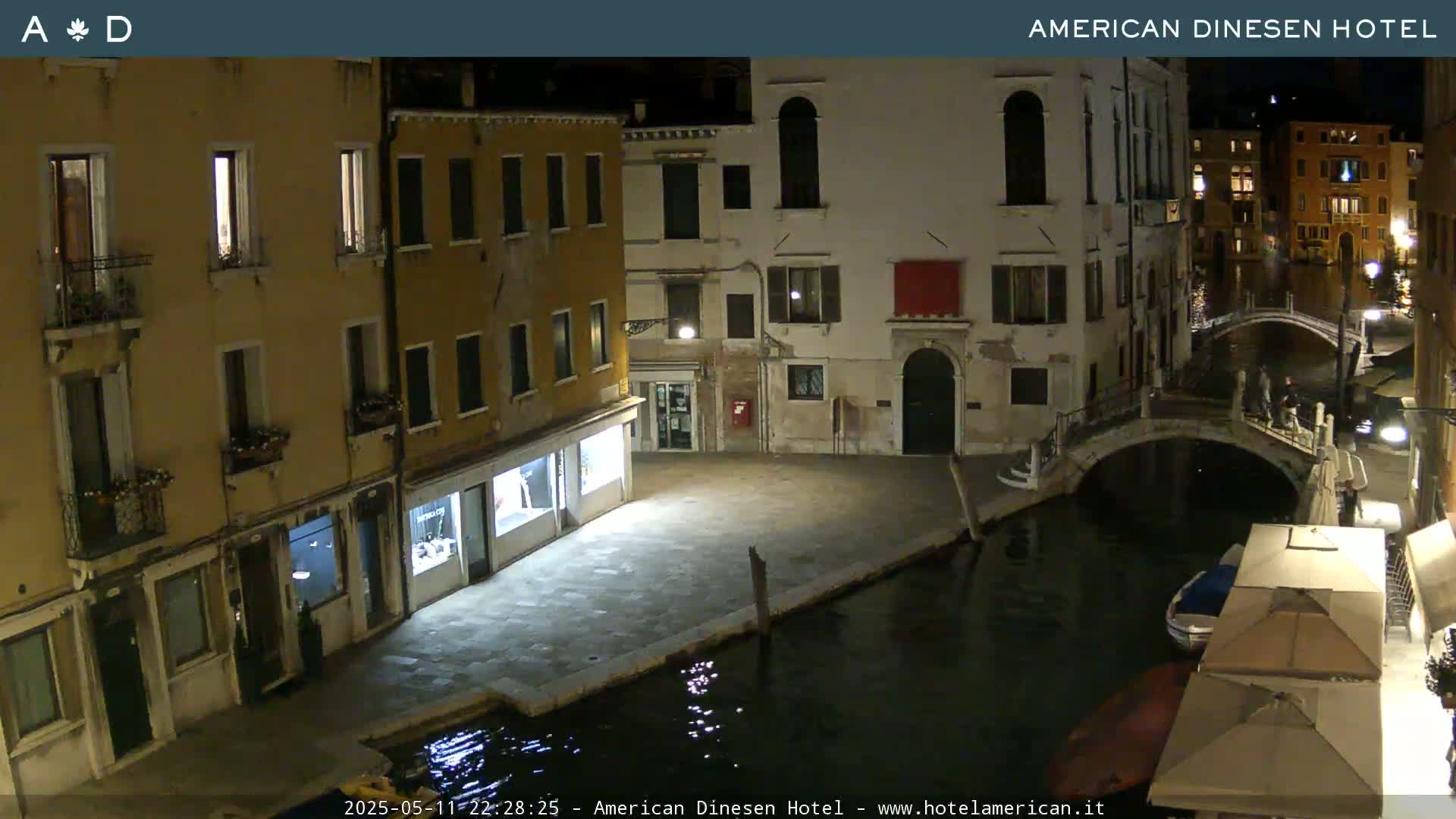 A nighttime view of a canal in Venice, Italy, showing buildings lining the waterway and a bridge crossing the canal.