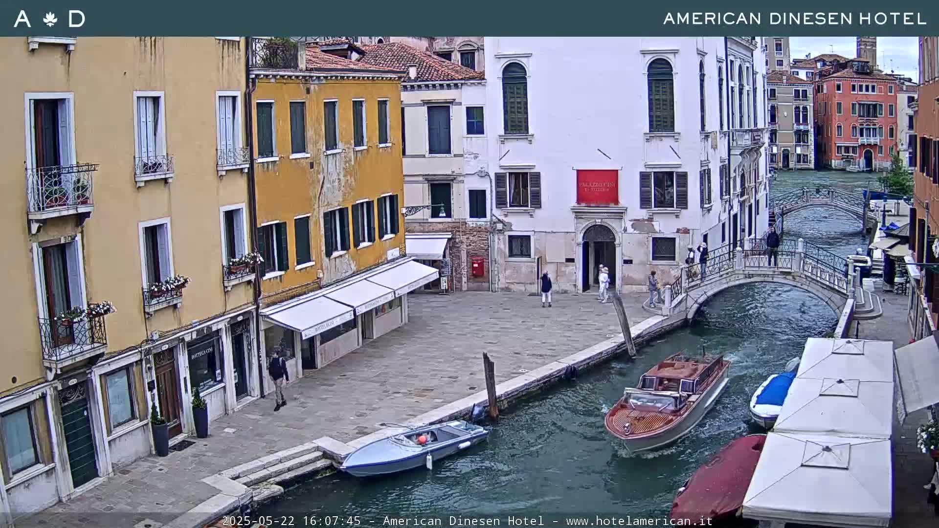 A canal in Venice, Italy, with several buildings lining the waterway, small boats moored along the canal's edge, and overcast skies.