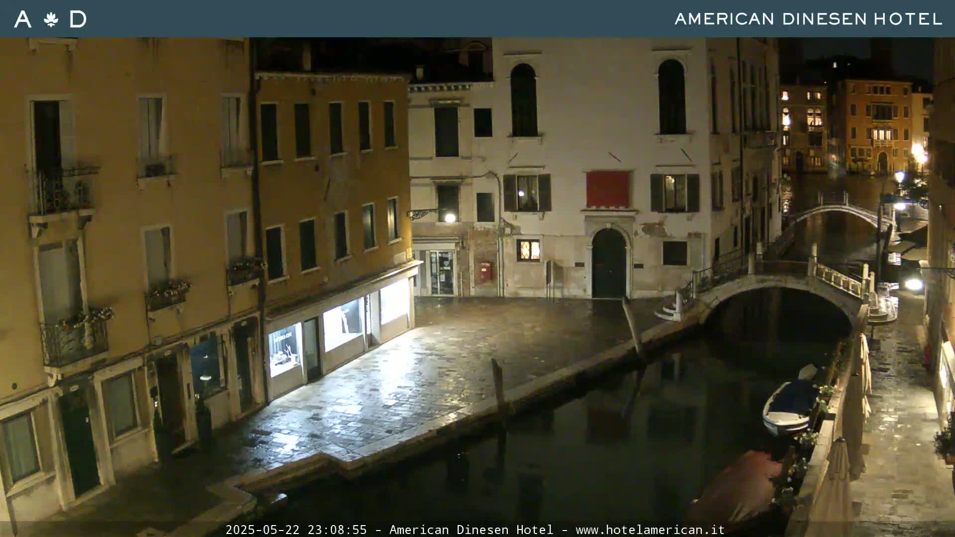 A nighttime view of a canal in Venice, with buildings lining the waterway and a small bridge crossing the canal.