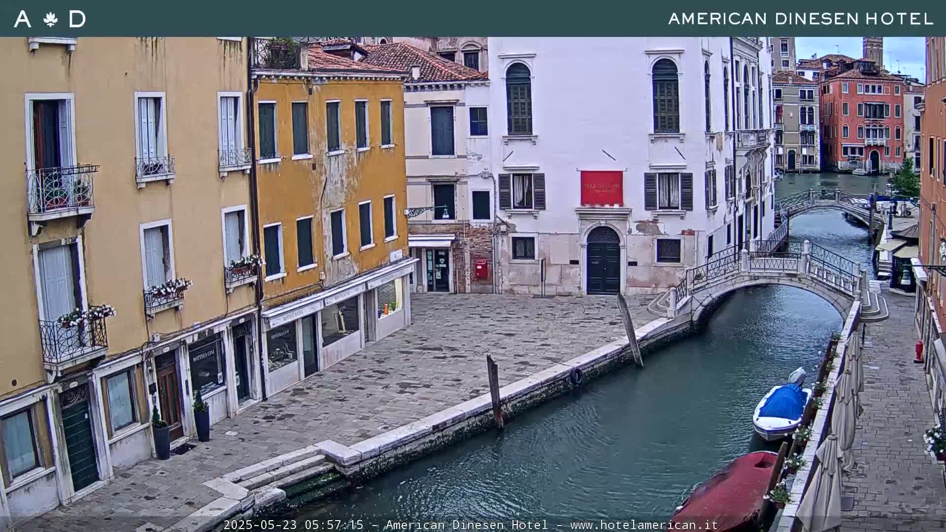 A view of a canal in Venice, Italy, with pastel-colored buildings lining the waterway and small bridges connecting the sidewalks.