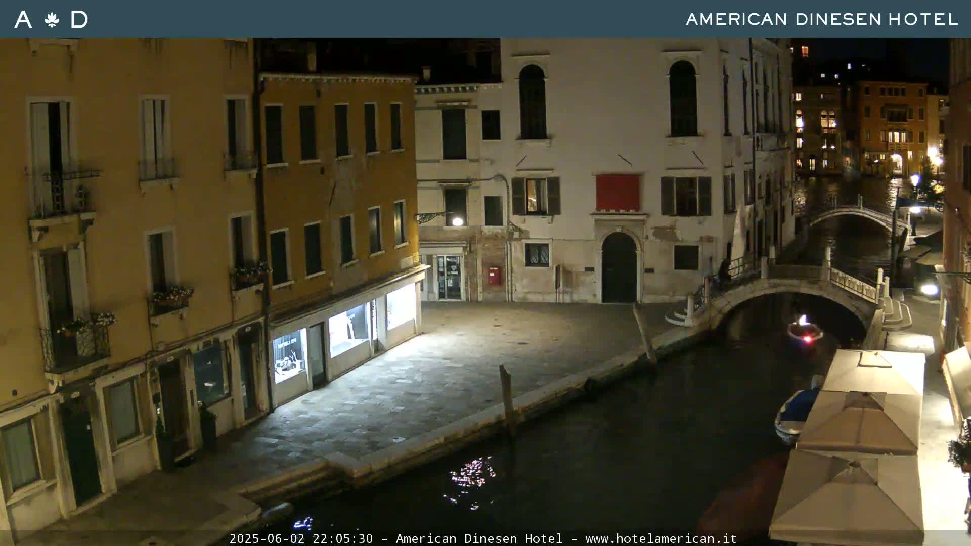A nighttime view of a canal in Venice, with several buildings lining the waterway and a small bridge spanning the canal.
