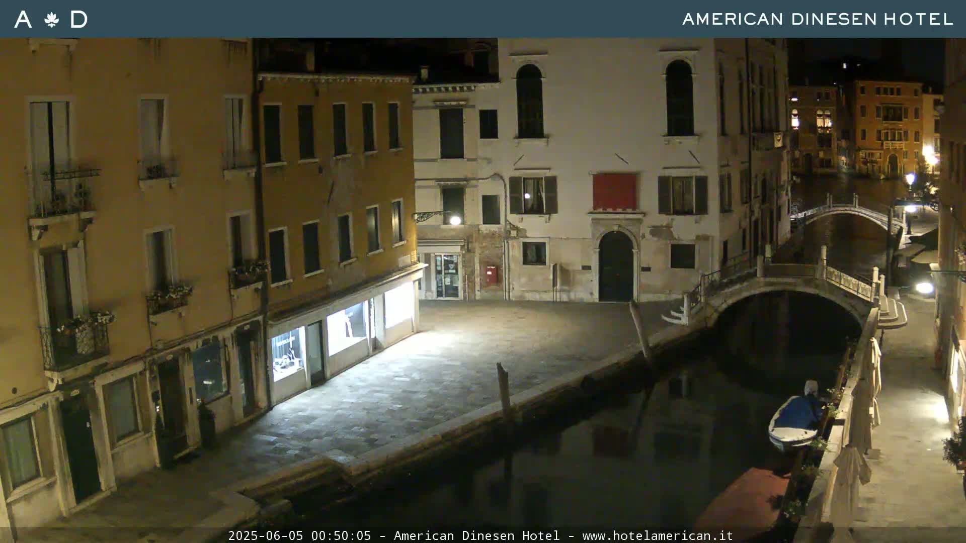 A nighttime view of a canal in Venice, showing several buildings along the waterway and a small boat moored nearby.