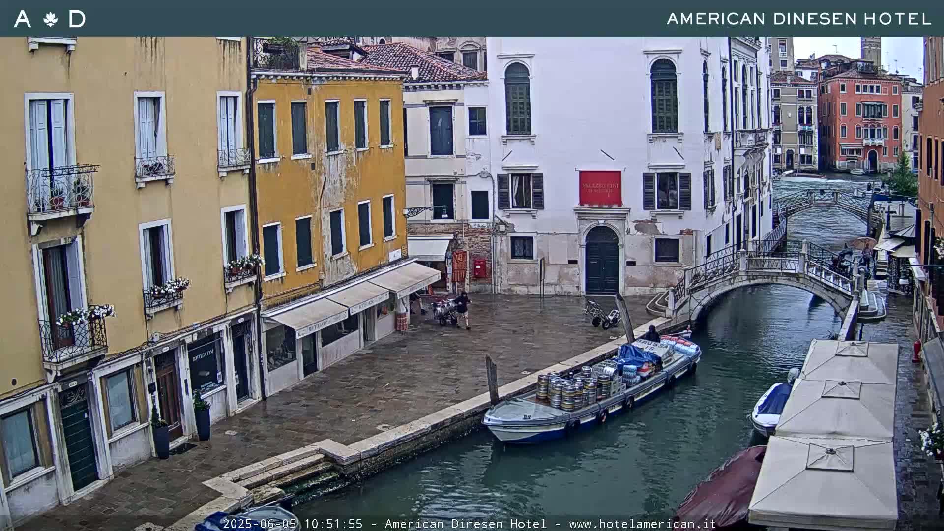 A canal in Venice, Italy, shows several buildings and a boat carrying barrels under a cloudy sky.