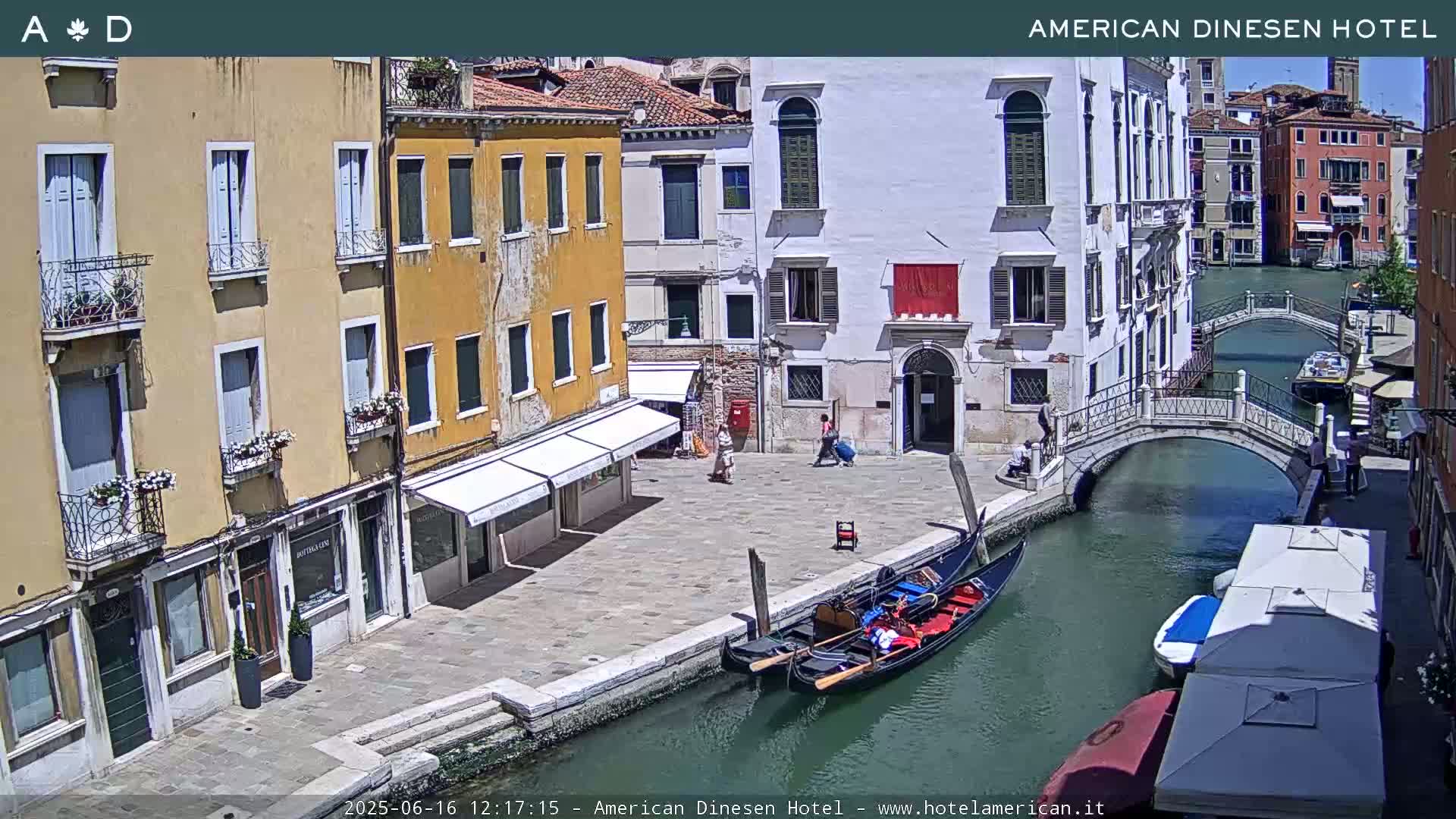 A sunny Venetian canal scene shows several buildings, a gondola, a small bridge, and some pedestrians.