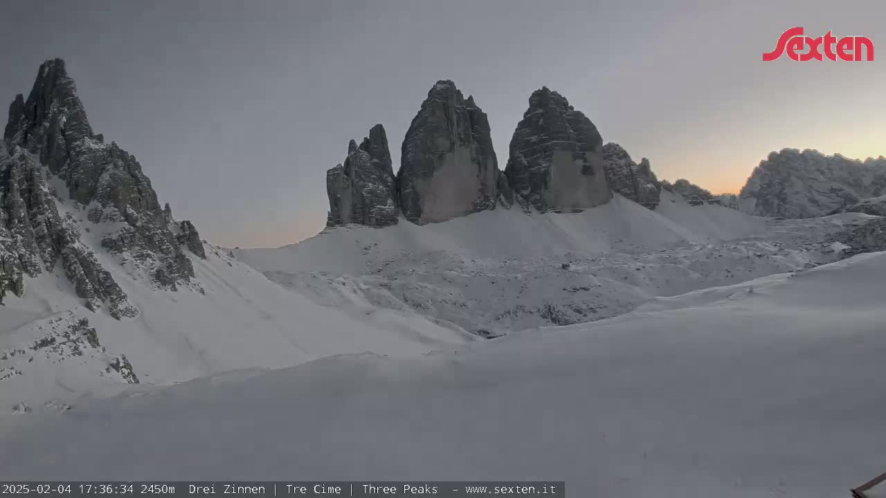A snow-covered mountain range with several prominent peaks is visible under a dusky sky.