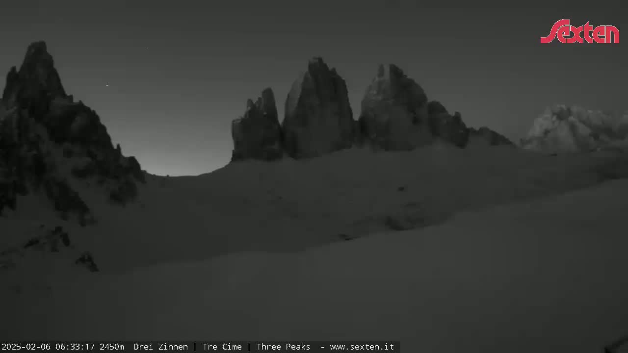 A snow-covered mountain range is visible under a dark, twilight sky.