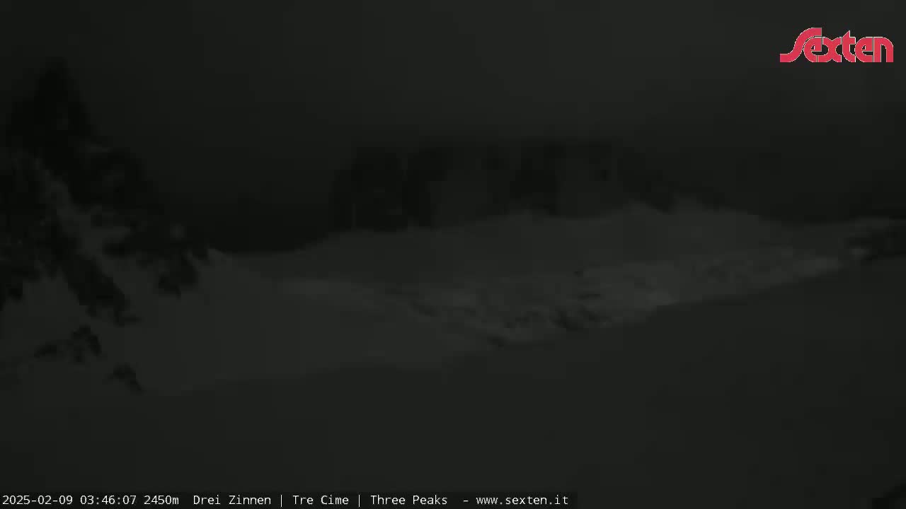 A dark, snowy landscape is visible at night, with indistinct shapes suggesting trees or mountains in the background.