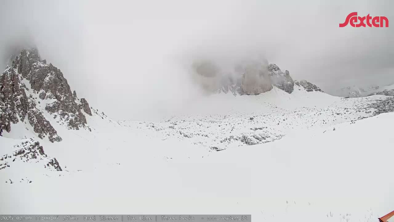 Snow-covered mountains are shrouded in fog.