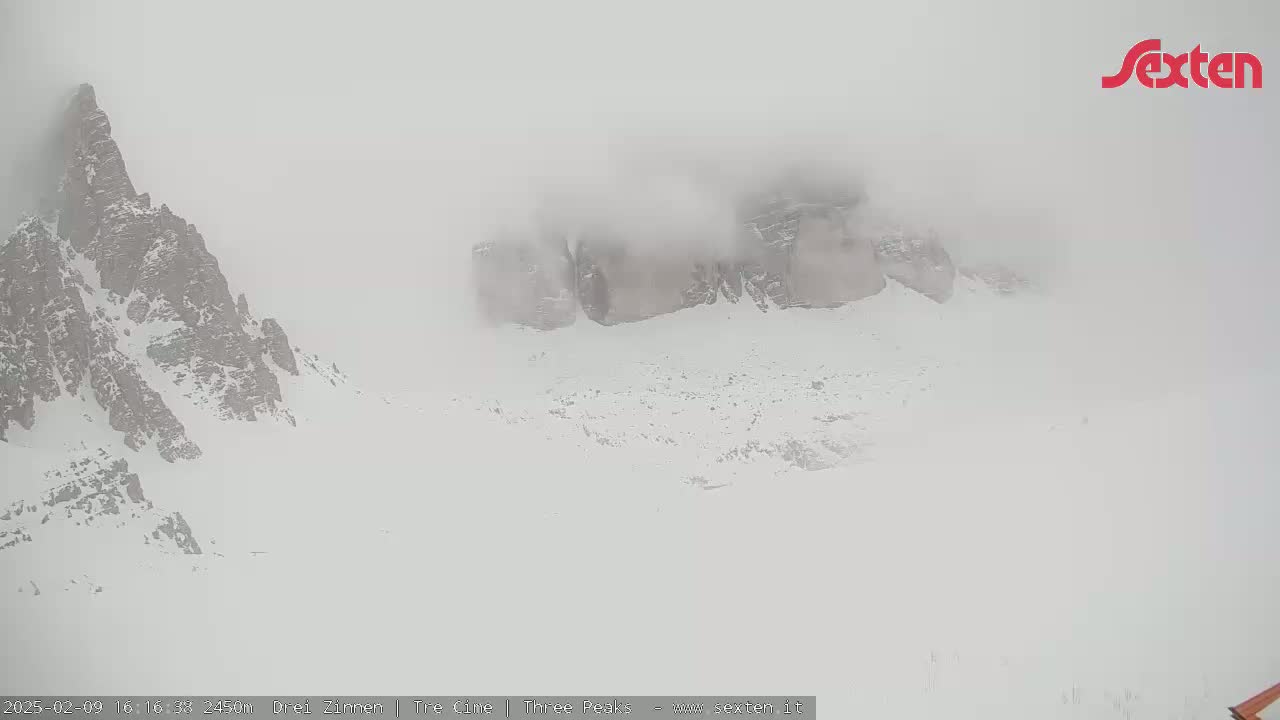 Snow-covered mountains are shrouded in thick fog.