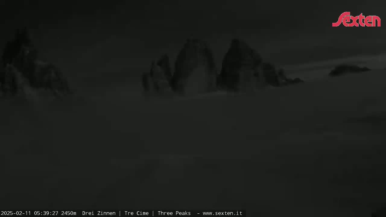 A nighttime, low-visibility view shows dark, indistinct mountain peaks shrouded in fog or mist.