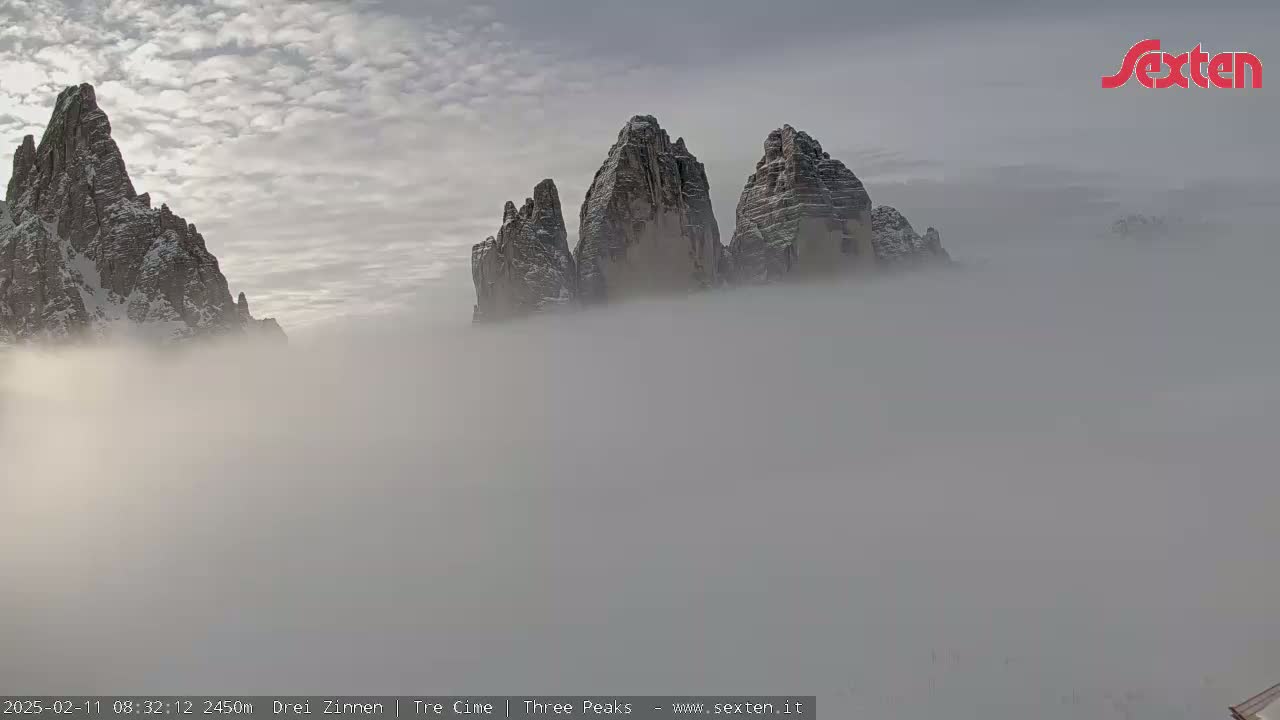 Snow-capped mountains partially obscured by a thick fog.