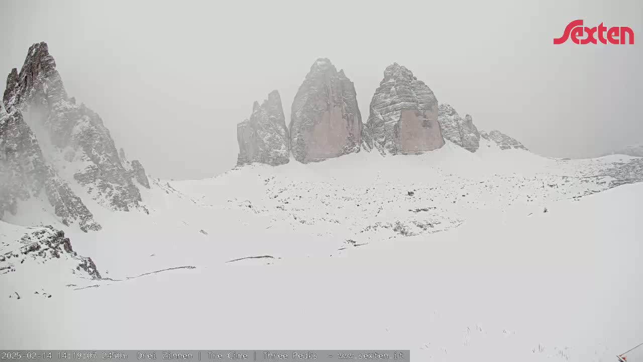 Snow-covered mountains rise in a hazy, snowy landscape.