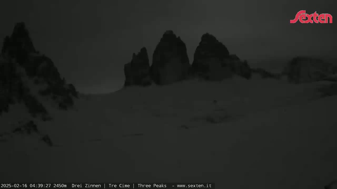 A dark, snowy landscape features several large, shadowy mountain peaks under a dim, overcast sky.