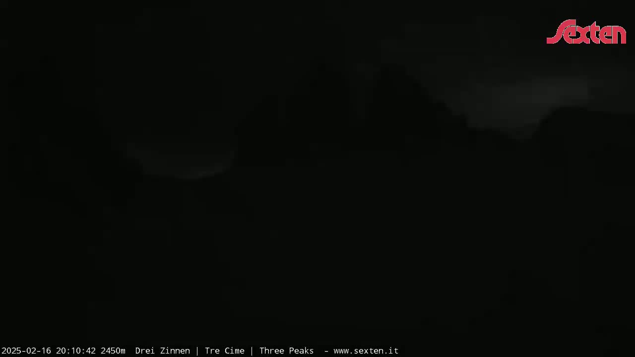 A dark, nighttime outdoor scene shows a mostly obscured landscape under a cloudy sky.