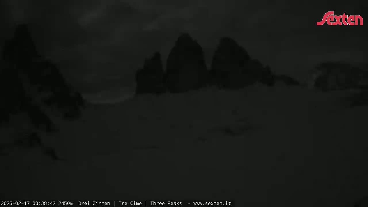 Three dark, indistinct peaks are visible under a cloudy, dark sky.