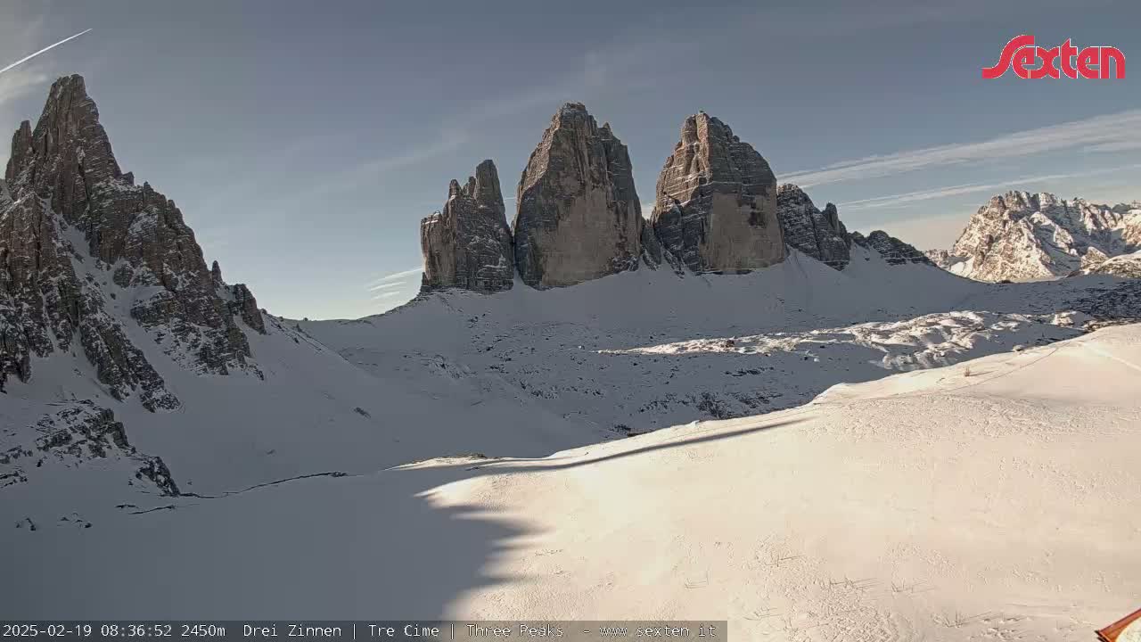 A snow-covered mountain range with several prominent peaks is visible under a mostly clear sky.