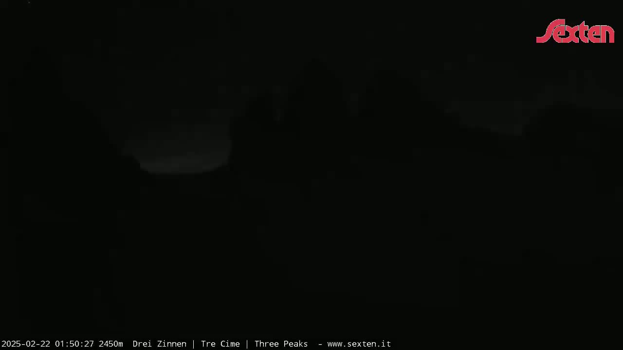 A very dark, nighttime outdoor scene shows a faintly illuminated area in the distance under a seemingly clear sky.