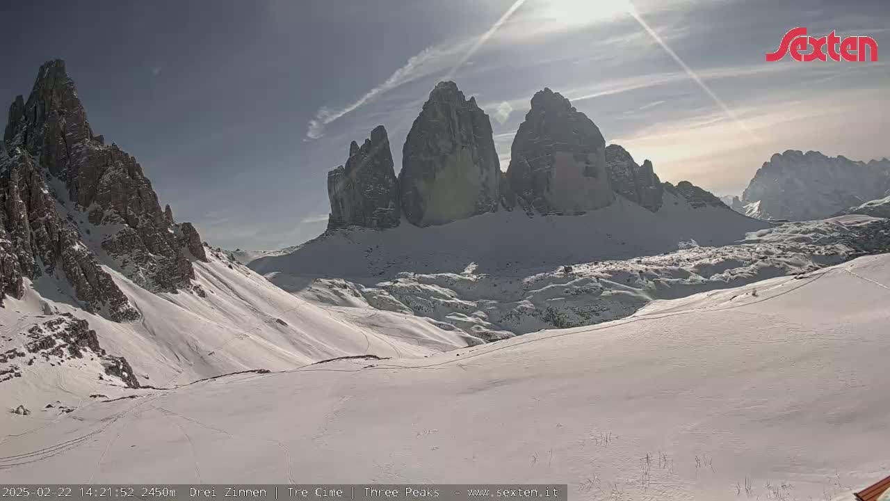 A snow-covered mountain range with several prominent peaks is visible under a mostly sunny sky.