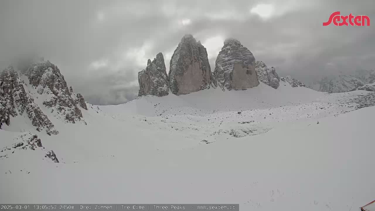 A snow-covered mountain range, with three prominent peaks, is visible under an overcast sky.