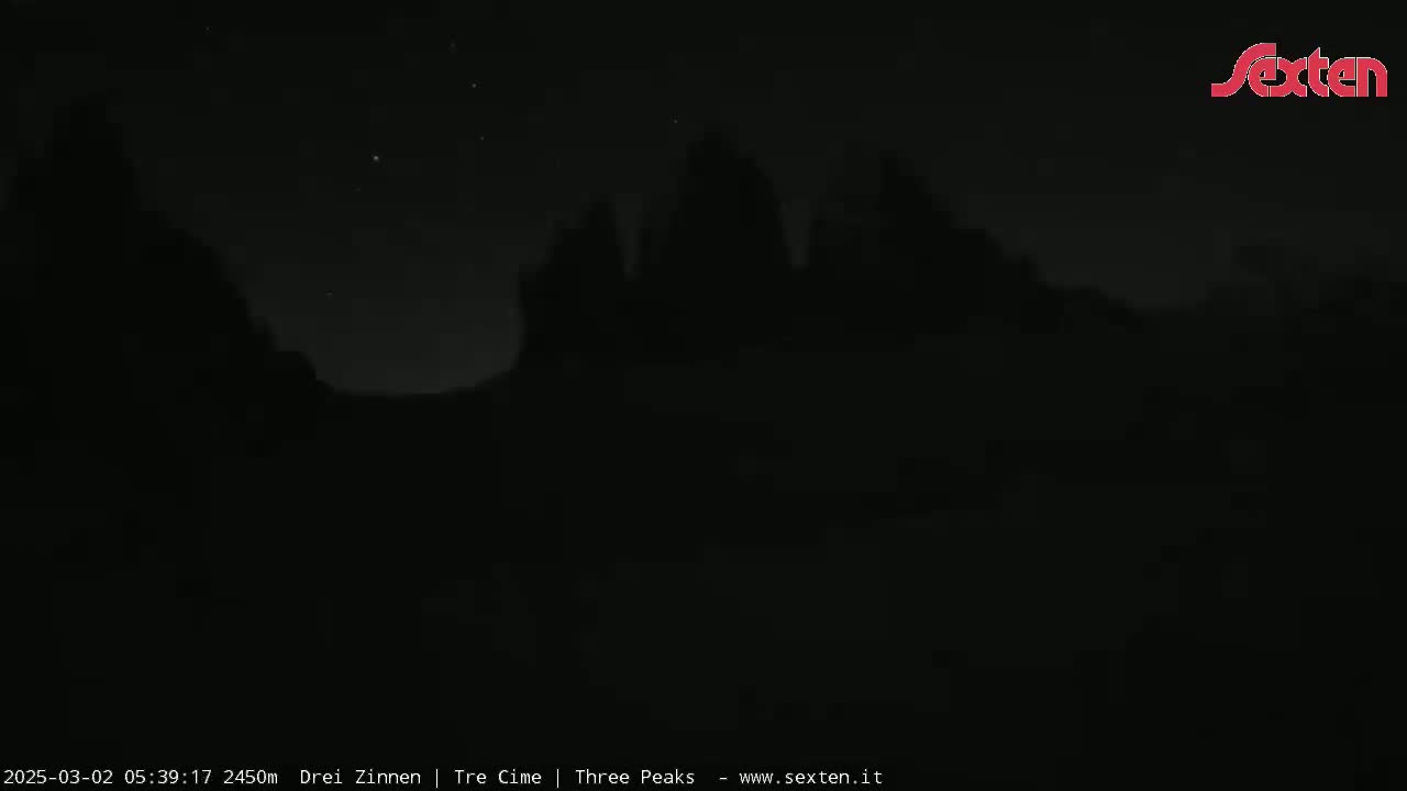 Silhouetted mountain peaks are visible under a dark, nighttime sky with a few stars.