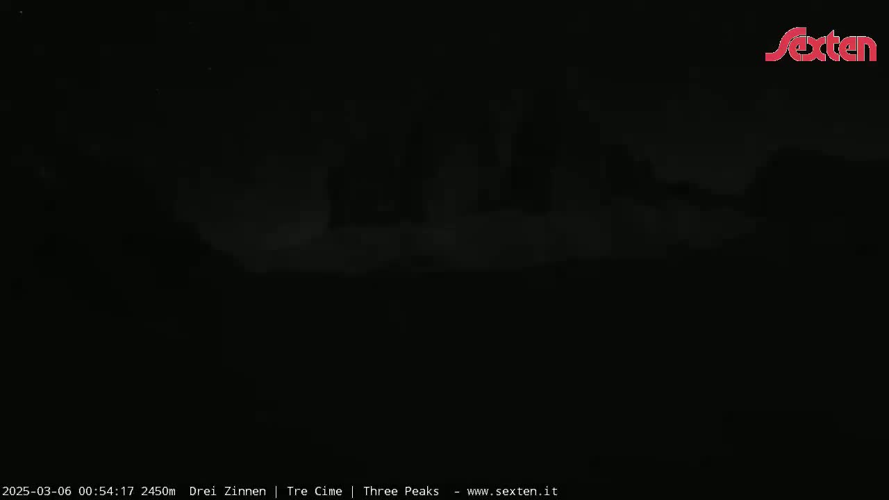 A dark, nighttime scene shows an indistinct, shadowy landscape under a cloudy sky.