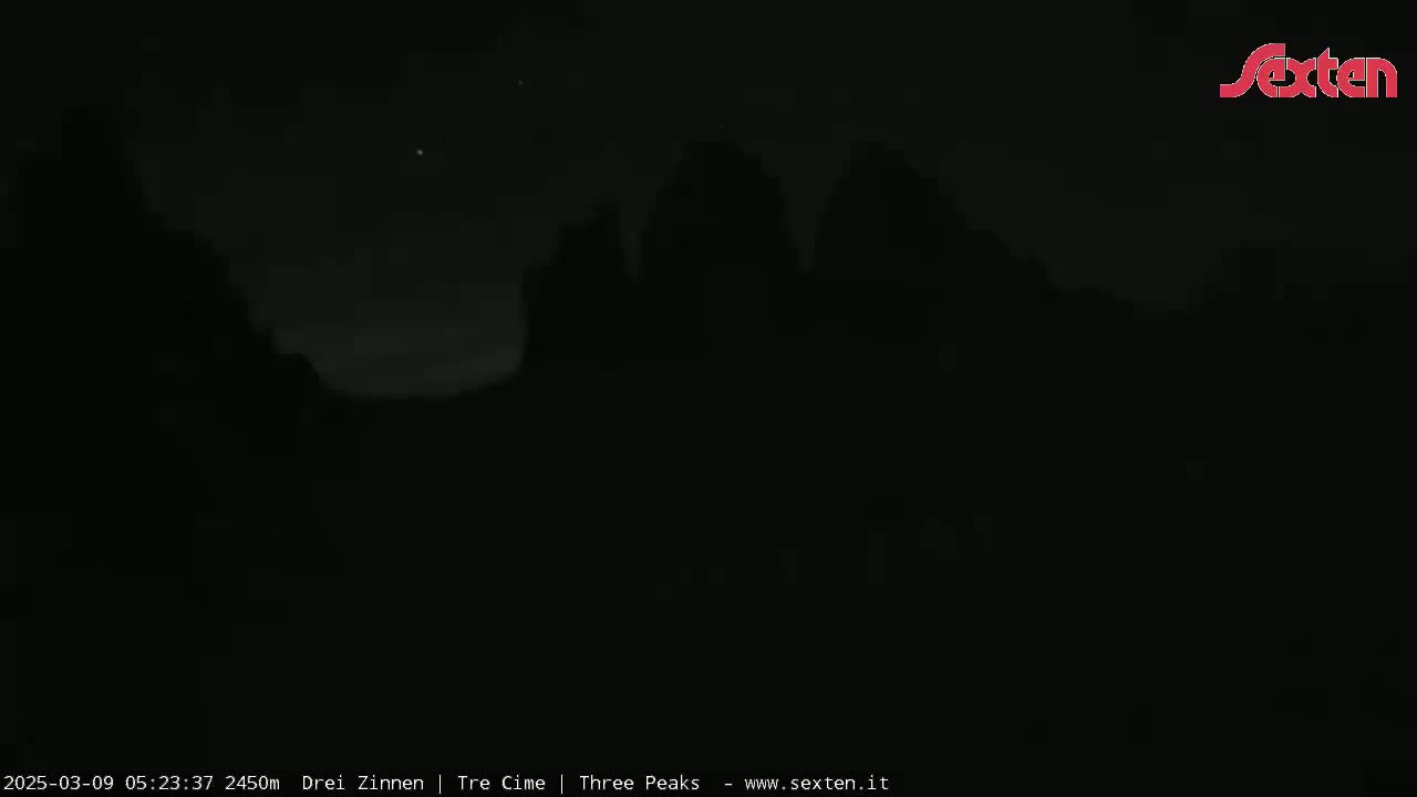 Silhouetted mountains are visible against a dark, night sky.