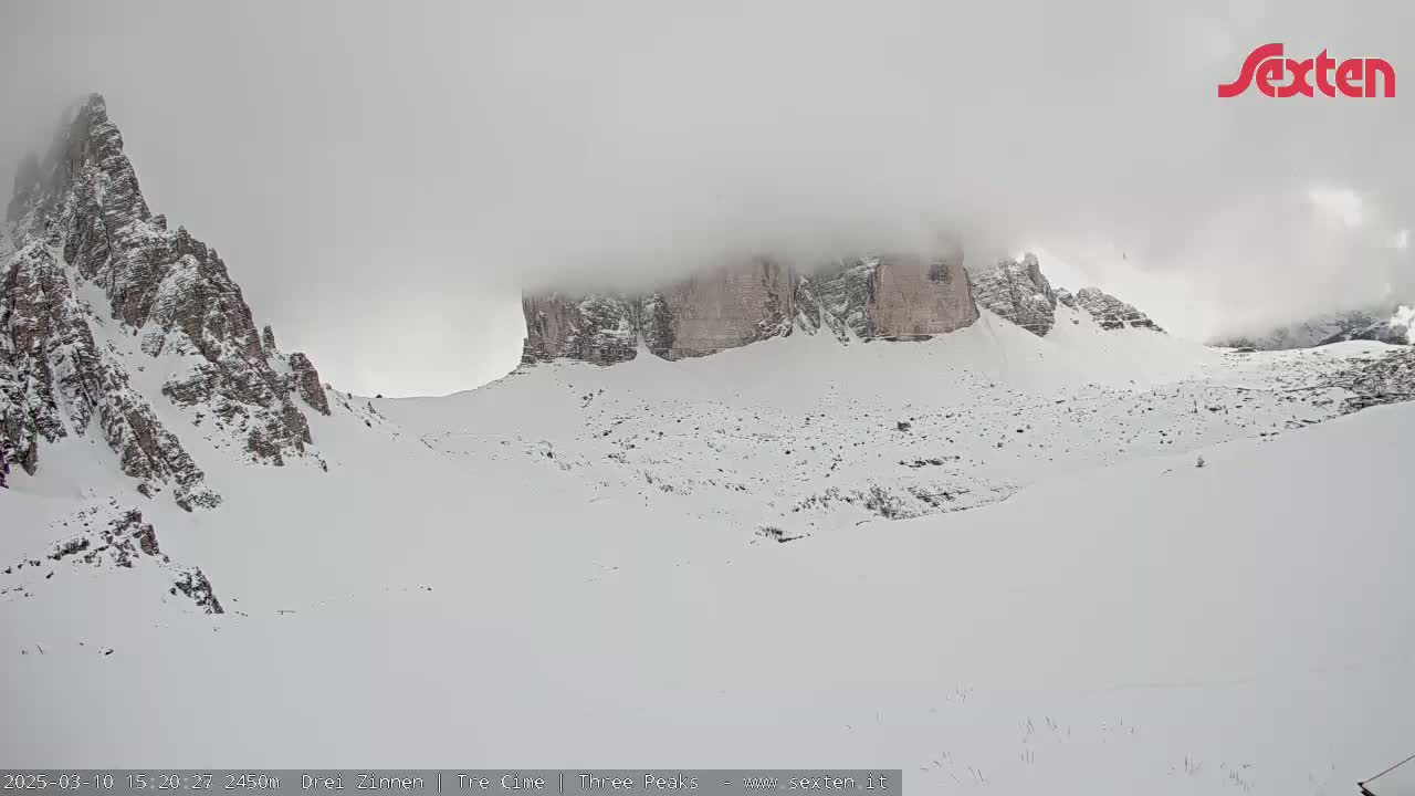 Snow-covered mountains are partially obscured by fog or clouds.
