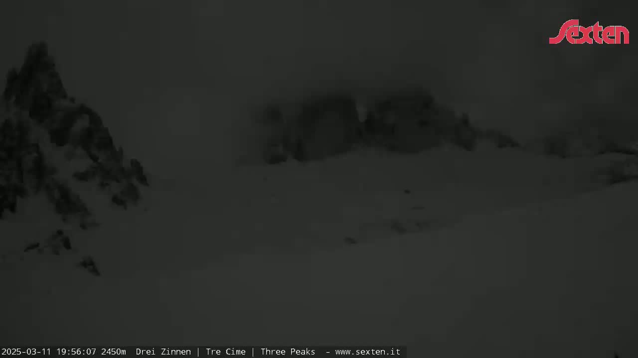 A snow-covered, mountainous landscape is visible under dark, nighttime conditions.