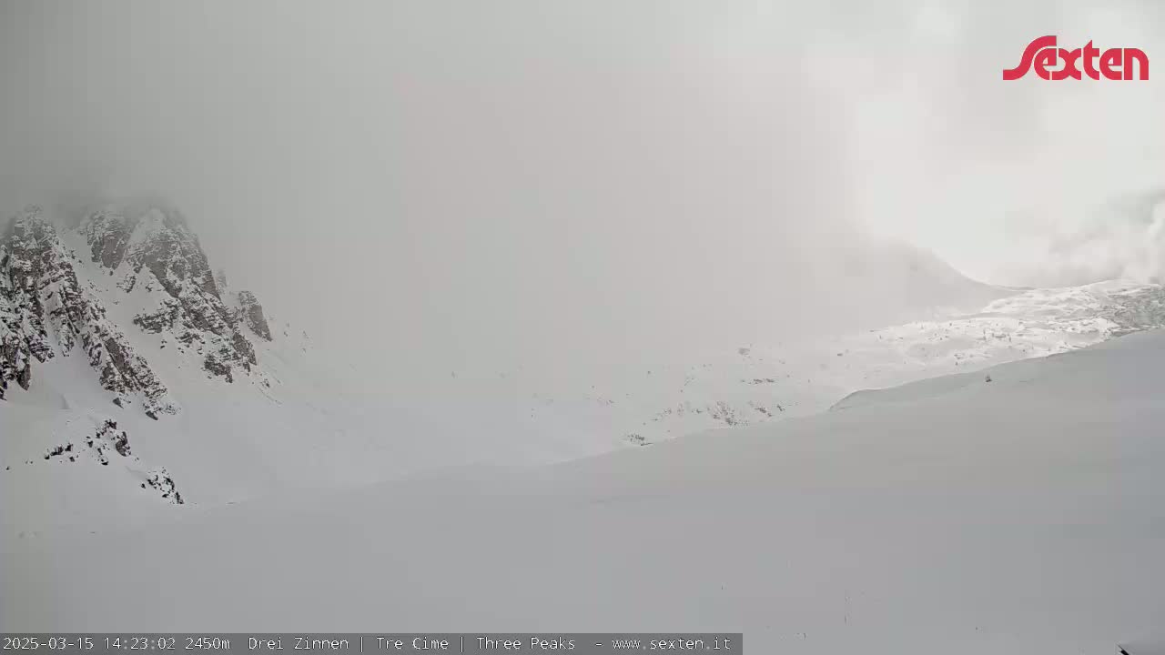 Snow-covered mountains are shrouded in heavy fog.