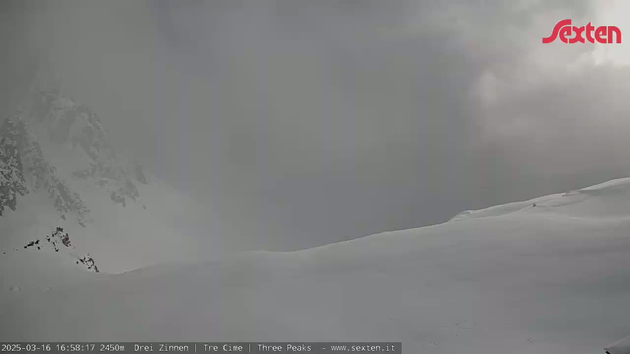 A snow-covered mountain peak is shrouded in heavy fog.