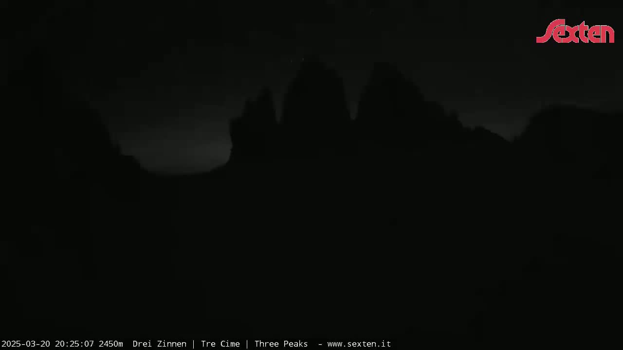A dark, nighttime image shows the silhouetted shapes of mountains under a mostly clear sky.