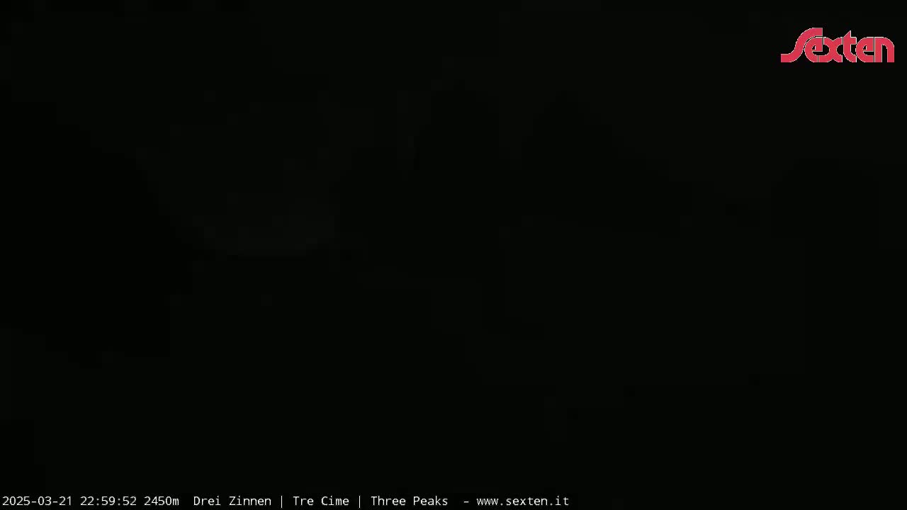 The image is completely black except for a faint, blurry light source in the upper center.