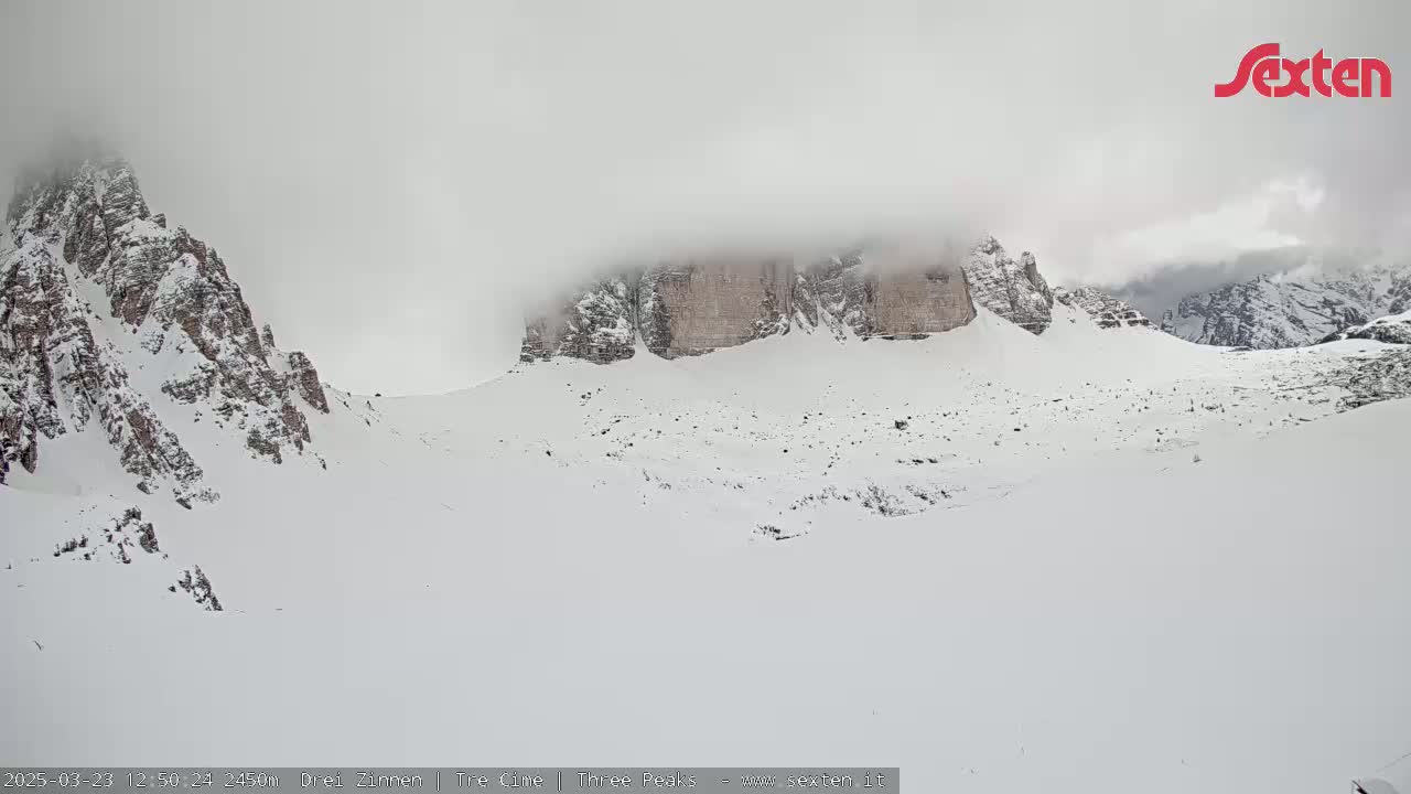 Snow-covered mountains are partially obscured by fog or clouds.