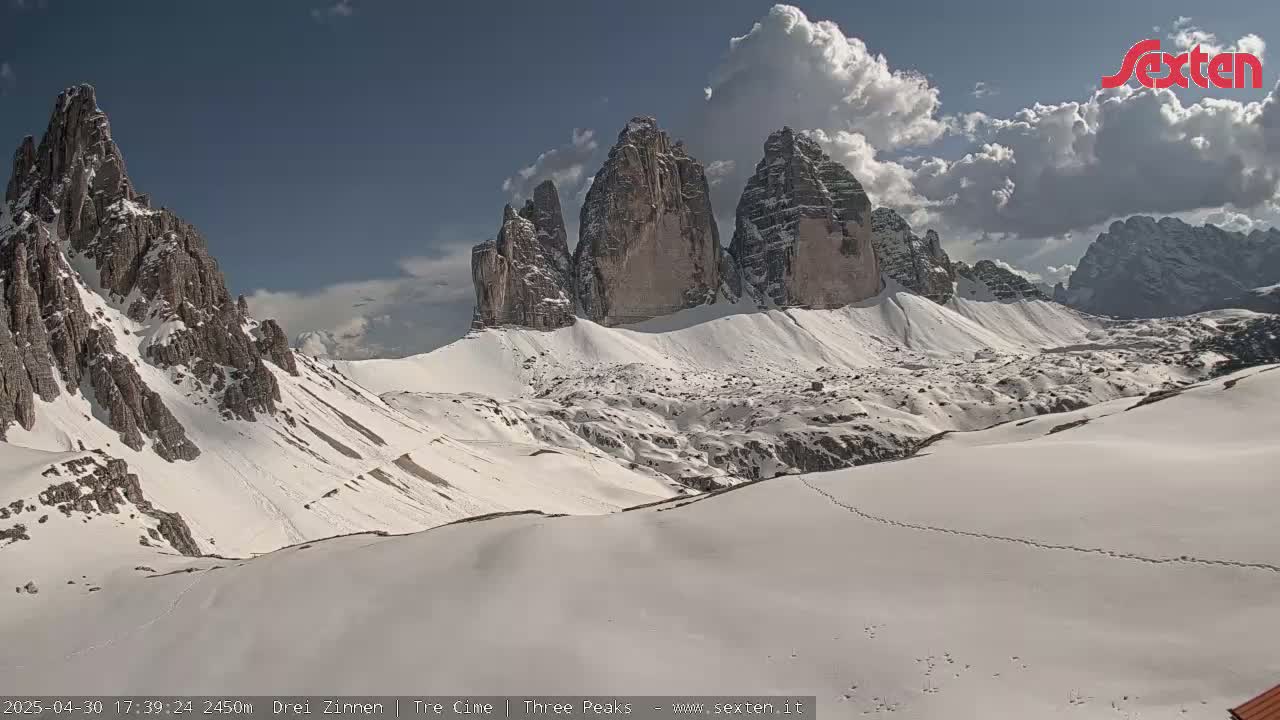 A snow-covered mountain range with several prominent peaks is visible under a partly cloudy sky.