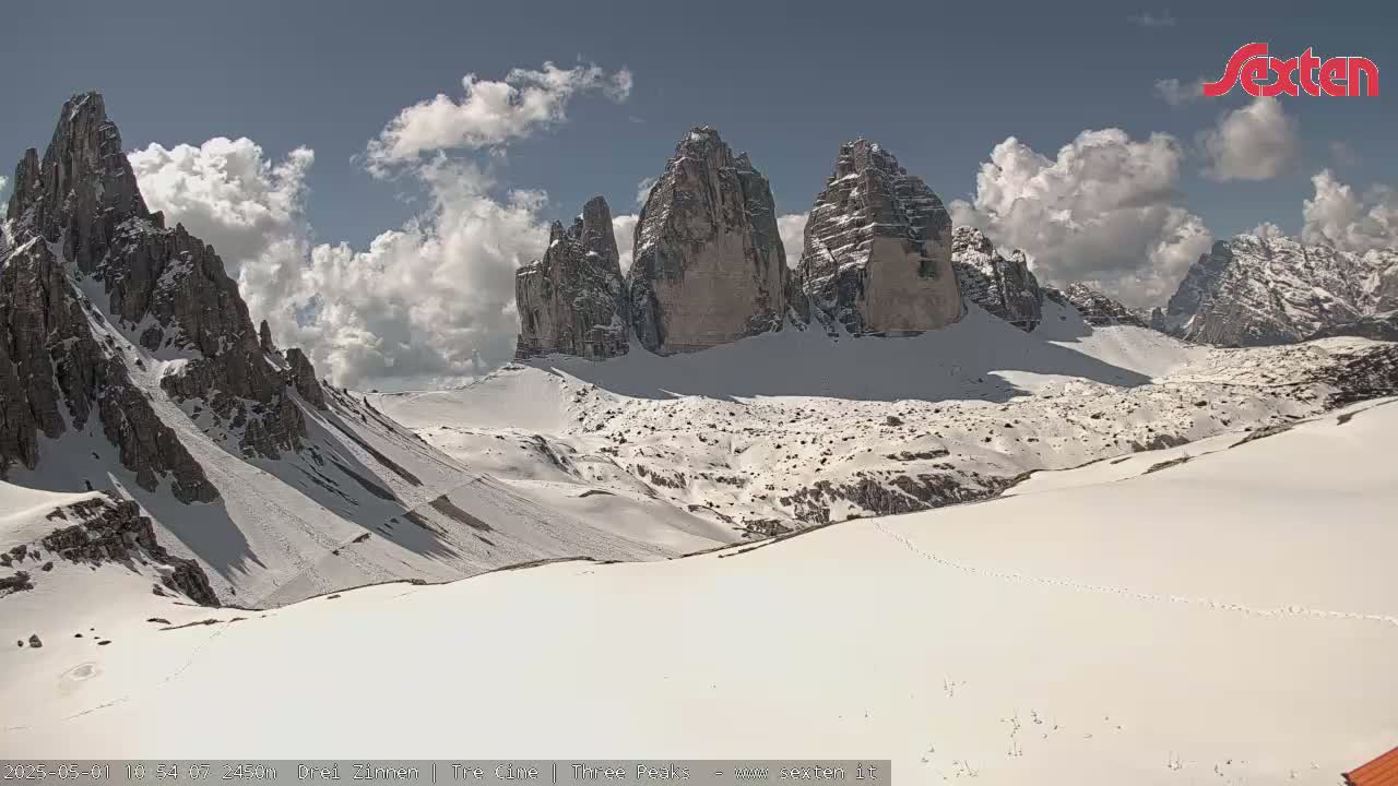 A snow-covered mountain range with several prominent peaks is visible under a partly cloudy sky.