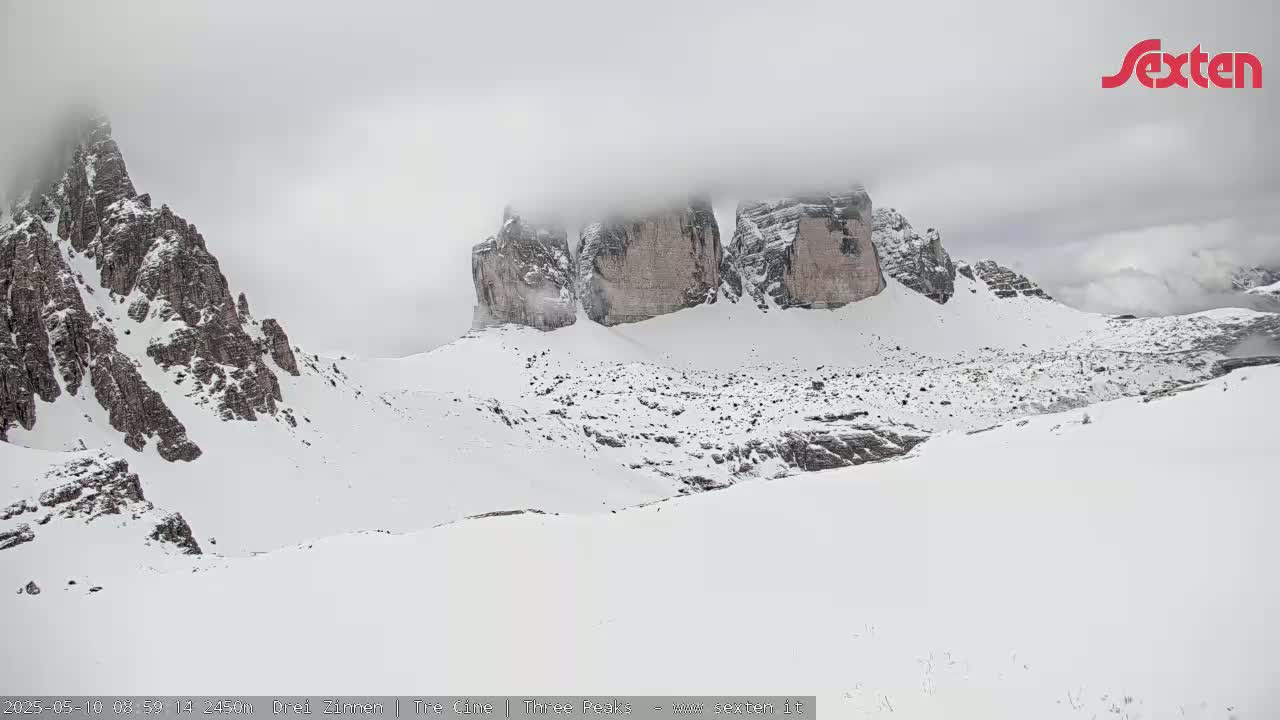 Snow-covered mountains, partially obscured by fog, are visible in a landscape of varying elevations.