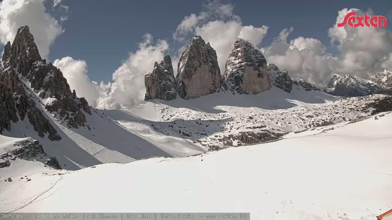 A snow-covered mountain range with several prominent peaks is visible under a partly cloudy sky.