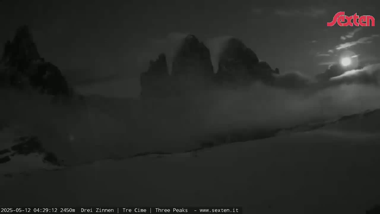A moonlit, foggy landscape features dark, snow-covered mountains in the distance.