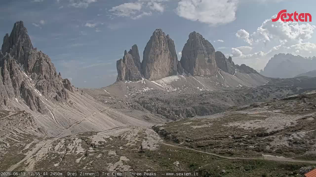 A mountain range with several tall, jagged peaks is visible under a partly cloudy sky.