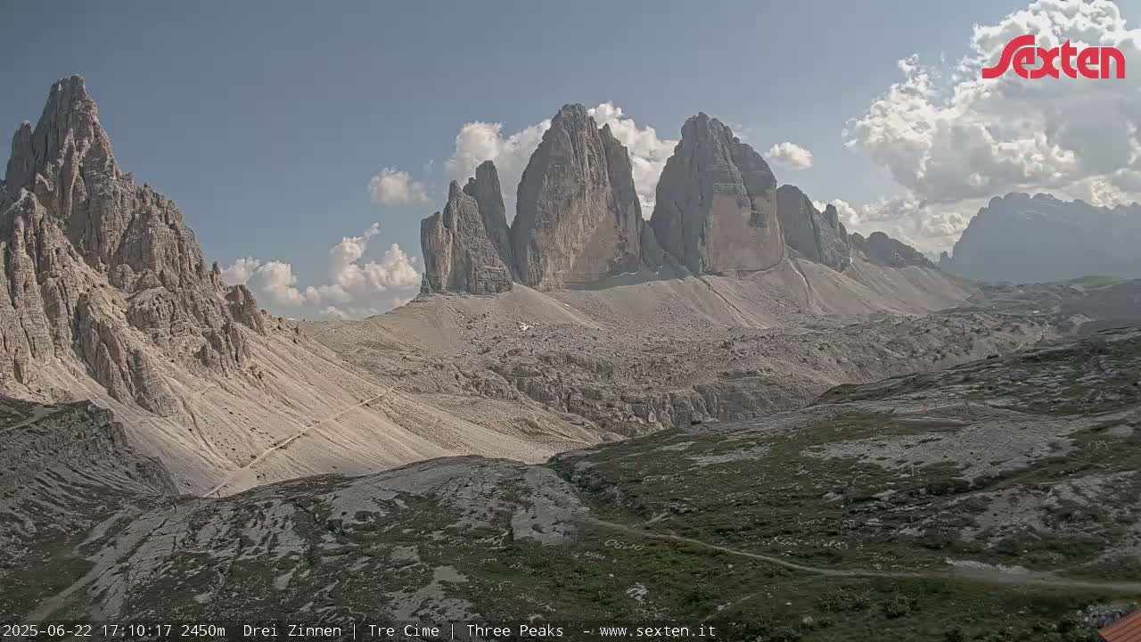 A partly cloudy day reveals a mountainous landscape with several prominent, jagged peaks.
