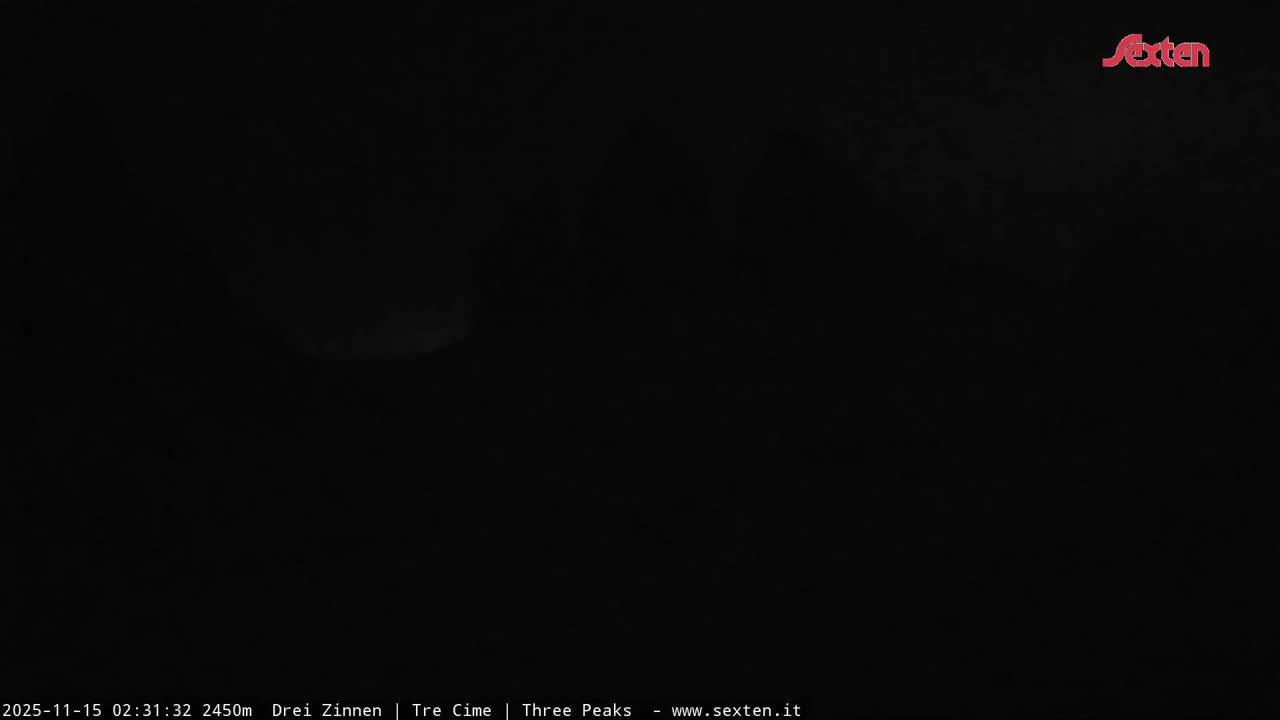 The image depicts an outdoor mountainous landscape under an extremely dark, pitch black night, with only faint, indistinct outlines of distant terrain barely visible against the dark sky.