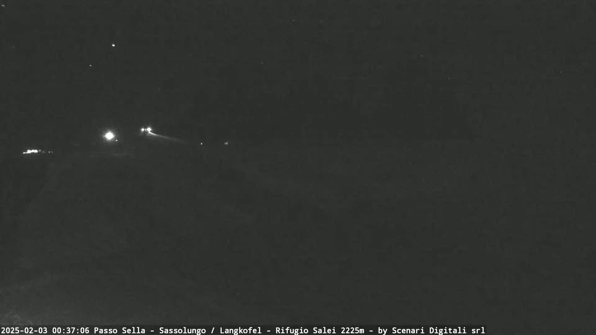 A nighttime long shot shows a dark road with a few distant headlights visible under a clear, starry sky.