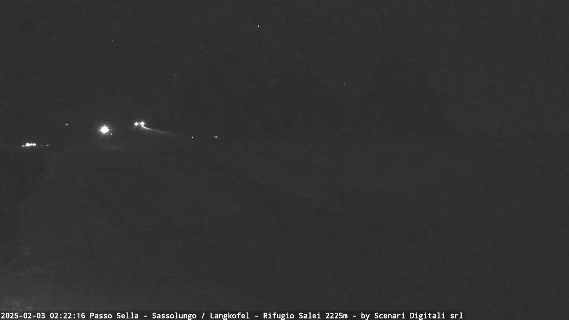 A nighttime, low-light view of a road with a few distant headlights visible.