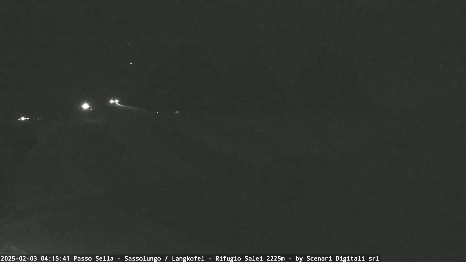 At night, a few distant headlights are visible on a dark road.
