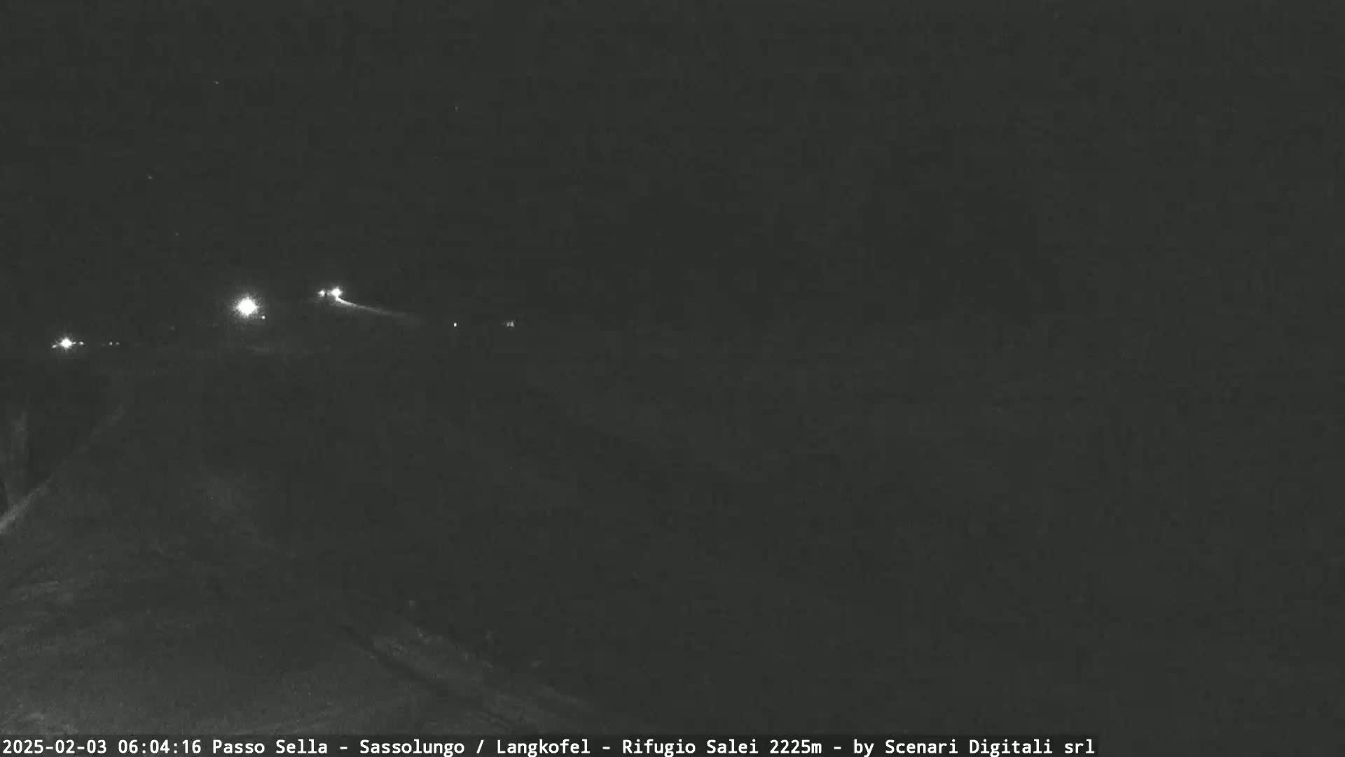 A nighttime, low-light view of a road with a few distant headlights visible.