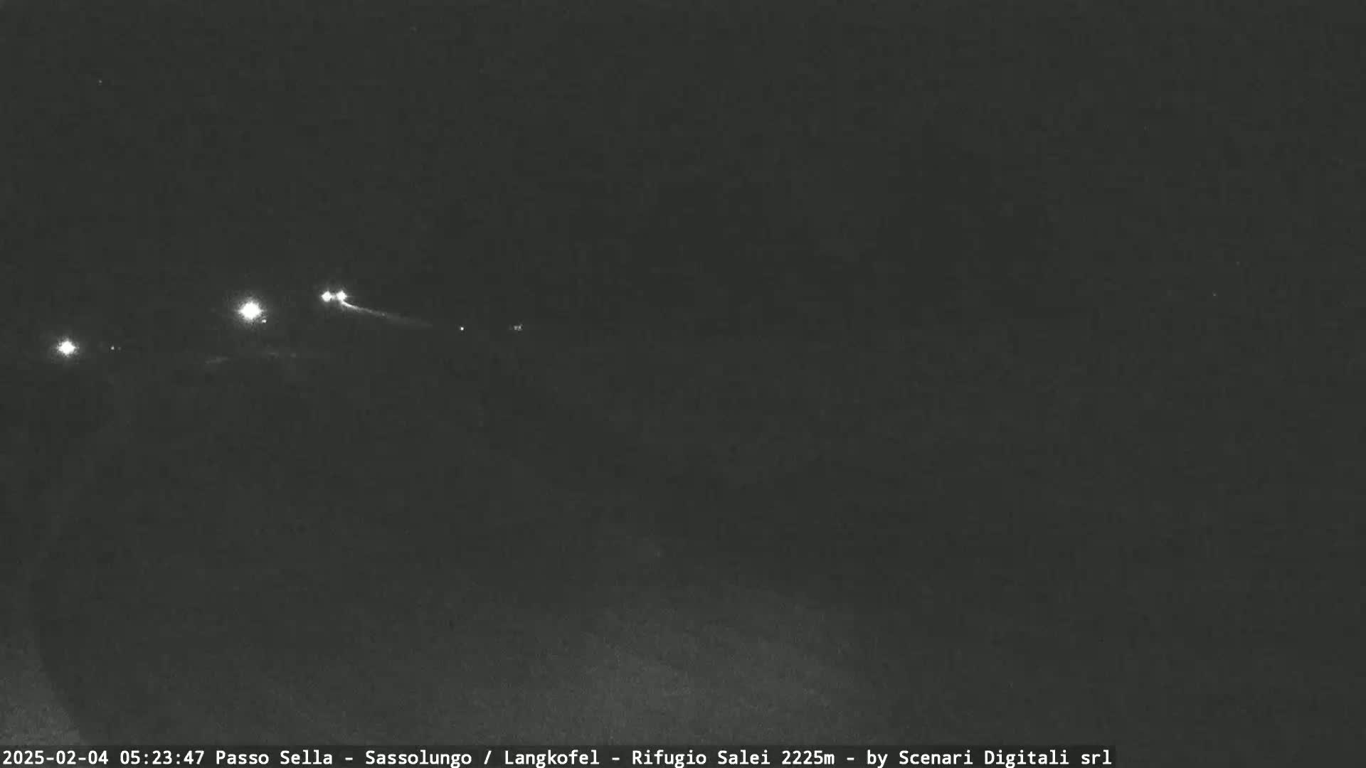 A nighttime, low-light view of a road with several distant headlights visible.